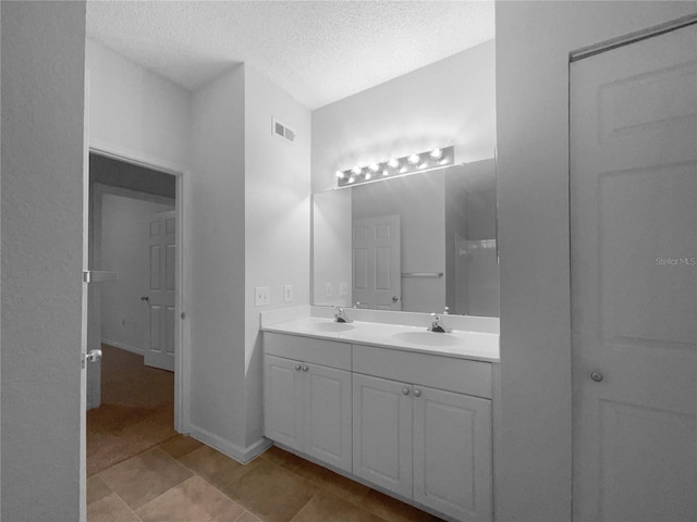 bathroom featuring a textured ceiling, tile patterned flooring, and vanity