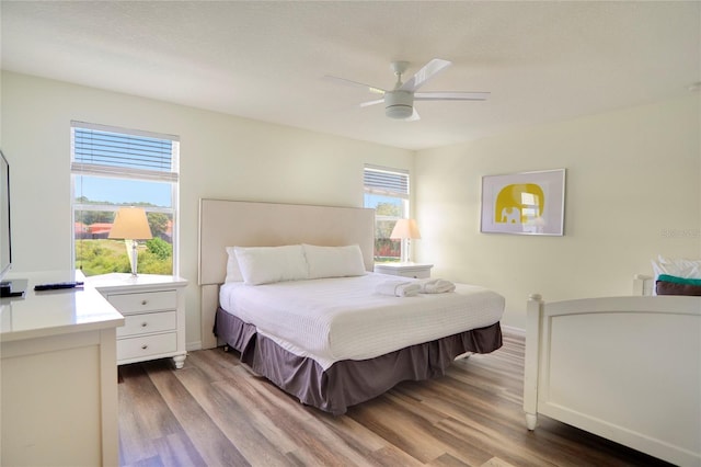 bedroom featuring wood-type flooring, multiple windows, and ceiling fan