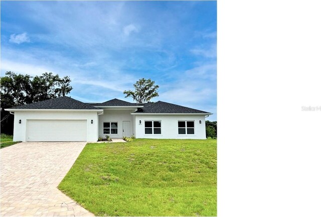 view of front of property with decorative driveway, an attached garage, stucco siding, and a front yard