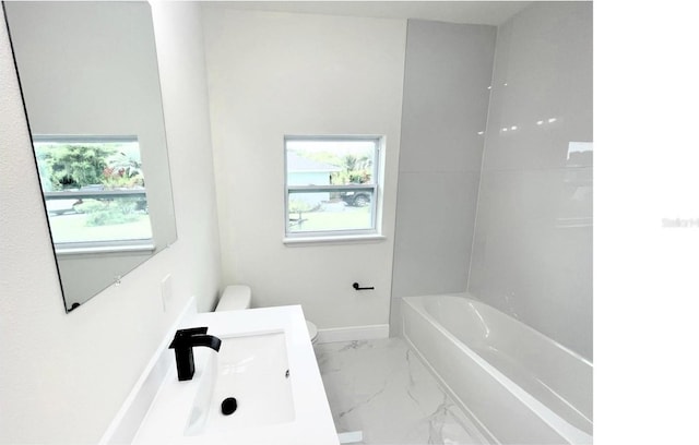 bathroom featuring marble finish floor, baseboards, a sink, and toilet