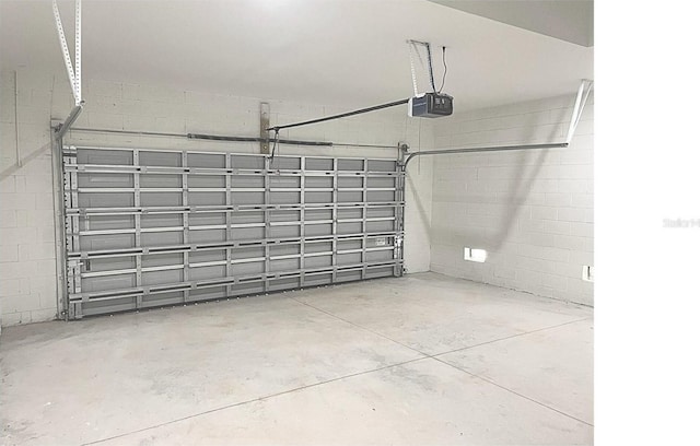 garage with concrete block wall and a garage door opener