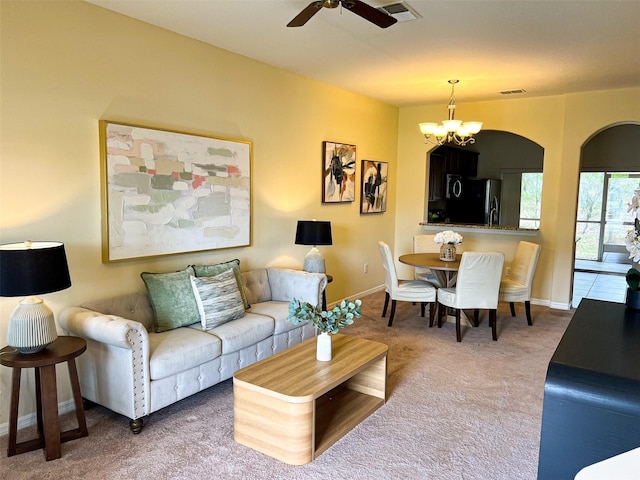 carpeted living room with ceiling fan with notable chandelier