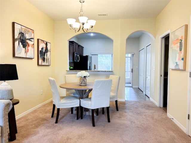 dining area with light carpet and an inviting chandelier