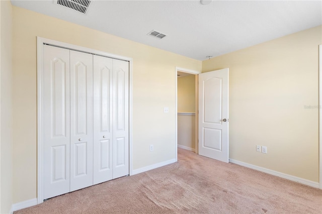 unfurnished bedroom with light carpet and a closet