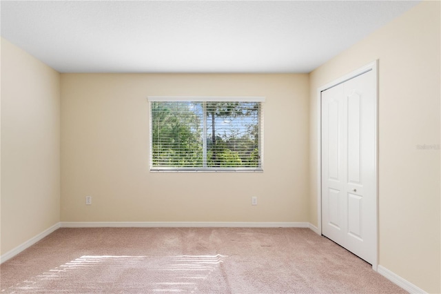 unfurnished bedroom with light carpet and a closet