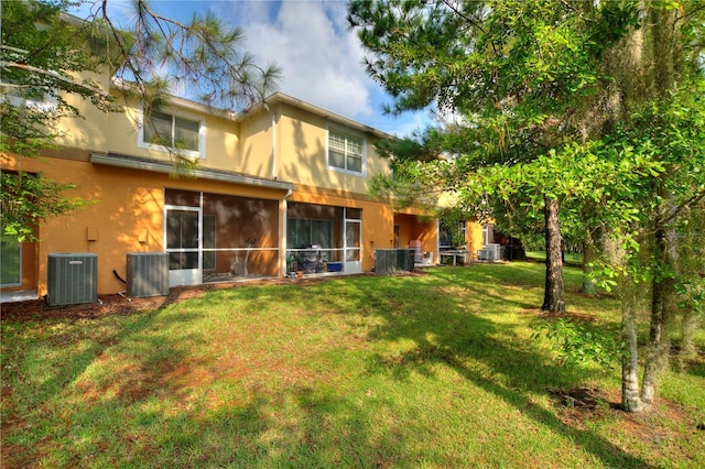 rear view of property with a sunroom, a lawn, and central air condition unit