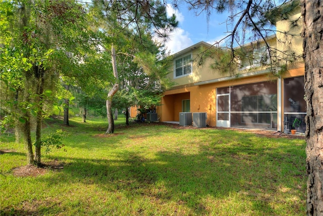 view of yard with central AC and a sunroom