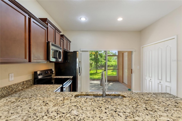 kitchen with appliances with stainless steel finishes, light stone countertops, and sink