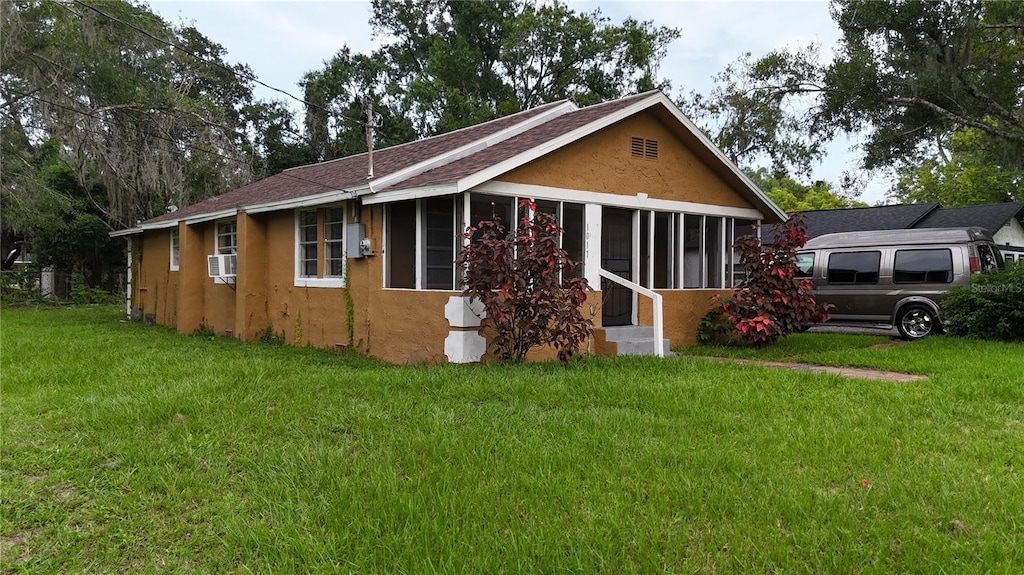 view of front of house with a front yard, cooling unit, and a sunroom