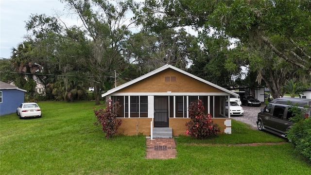 bungalow-style home with a front yard and a sunroom