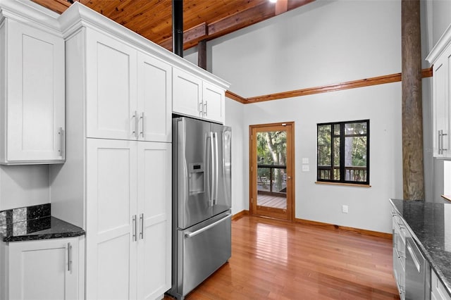 kitchen featuring dark stone counters, appliances with stainless steel finishes, light wood-style flooring, and white cabinetry