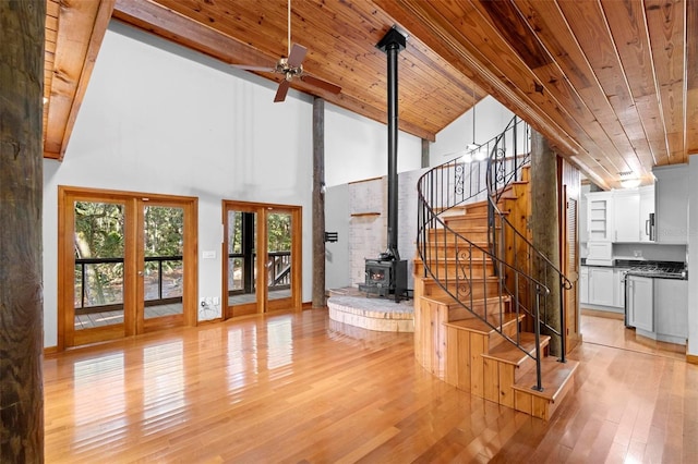 staircase featuring high vaulted ceiling, wooden ceiling, wood-type flooring, and a wood stove