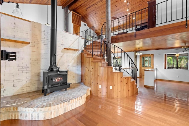 living room featuring wooden ceiling, stairway, hardwood / wood-style floors, a wood stove, and high vaulted ceiling