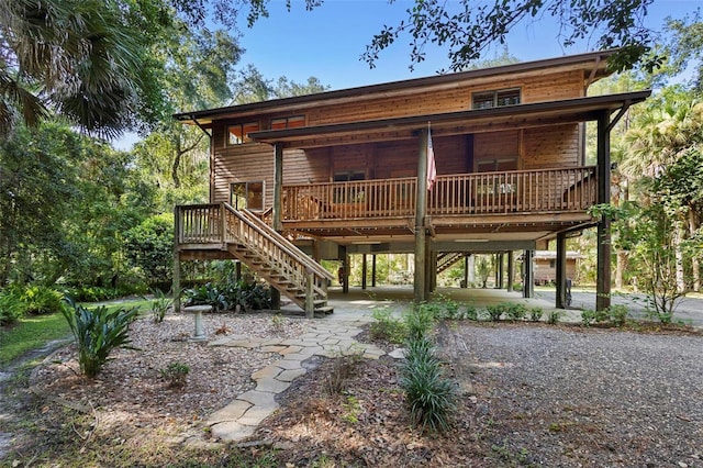 rear view of house with driveway, covered porch, stairs, and a carport