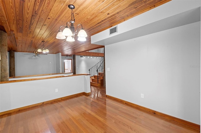 unfurnished room featuring baseboards, visible vents, stairway, wood finished floors, and an inviting chandelier