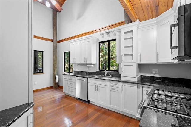 kitchen featuring wood-type flooring, appliances with stainless steel finishes, white cabinetry, a sink, and high vaulted ceiling