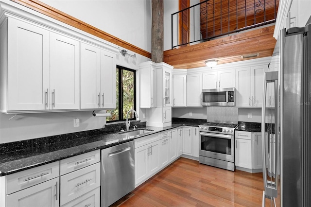 kitchen with white cabinets, light wood-style flooring, stainless steel appliances, and a sink