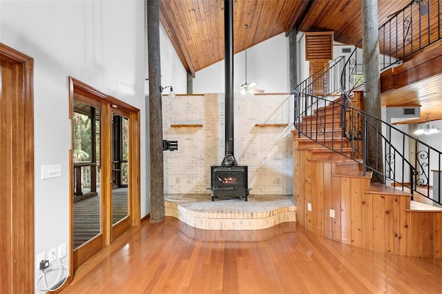 unfurnished living room with wooden ceiling, stairway, a wood stove, and wood finished floors