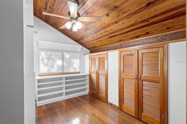 unfurnished bedroom featuring a ceiling fan, wood ceiling, wood-type flooring, vaulted ceiling, and multiple closets