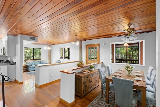 kitchen with visible vents, hanging light fixtures, an inviting chandelier, appliances with stainless steel finishes, and wood finished floors