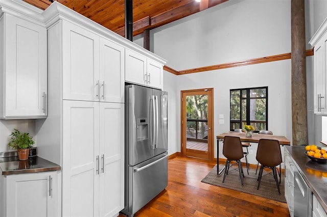 kitchen with dark wood finished floors, stainless steel counters, a towering ceiling, appliances with stainless steel finishes, and white cabinets