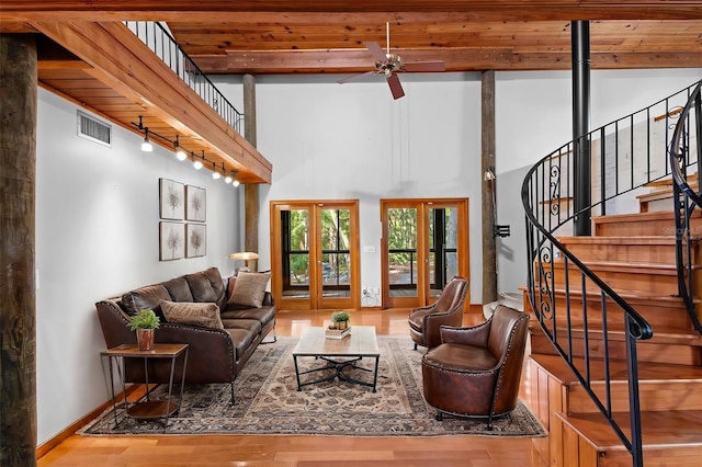 living area with french doors, visible vents, wood finished floors, baseboards, and stairs