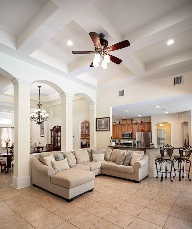 living room with a high ceiling, coffered ceiling, light tile patterned floors, and ornate columns