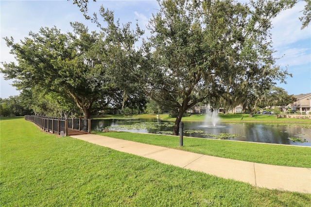 view of home's community with a water view and a lawn