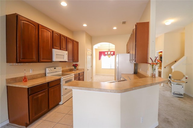 kitchen with light tile patterned flooring, white appliances, kitchen peninsula, and sink