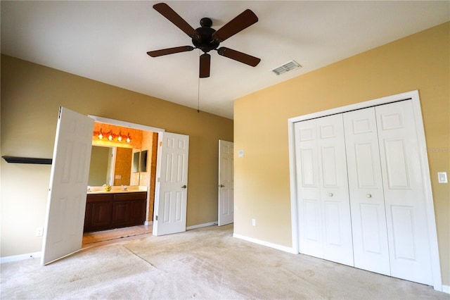 unfurnished bedroom with light colored carpet, a closet, ceiling fan, and ensuite bathroom