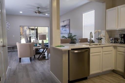 kitchen featuring sink, light hardwood / wood-style flooring, ceiling fan, stainless steel dishwasher, and kitchen peninsula