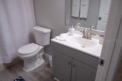 bathroom featuring walk in shower, vanity, toilet, and hardwood / wood-style floors