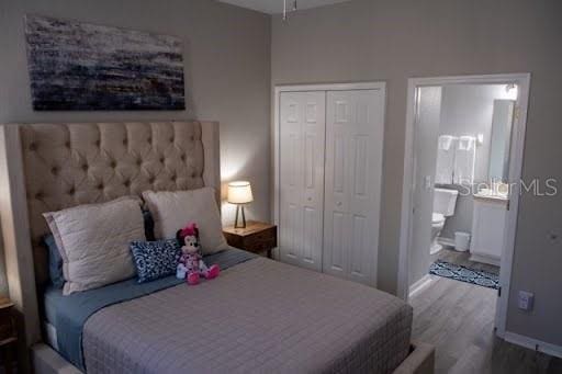 bedroom with hardwood / wood-style flooring, ensuite bath, and a closet