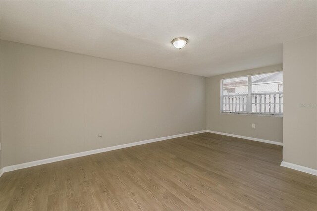 empty room with hardwood / wood-style floors and a textured ceiling