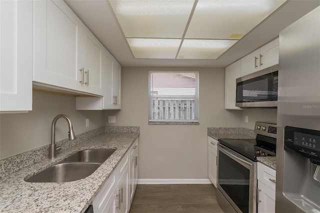 kitchen with white cabinetry, stainless steel appliances, sink, light stone counters, and dark hardwood / wood-style floors