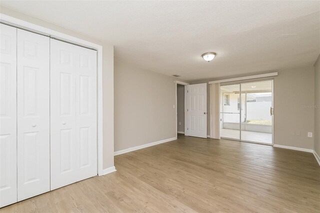 unfurnished bedroom featuring light wood-type flooring and a textured ceiling