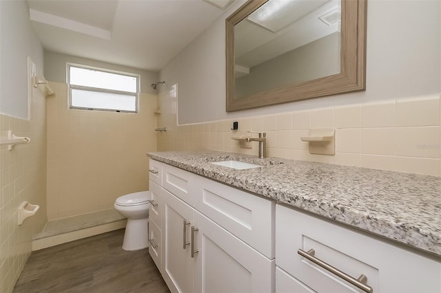 bathroom featuring tasteful backsplash, tile walls, toilet, vanity, and wood-type flooring