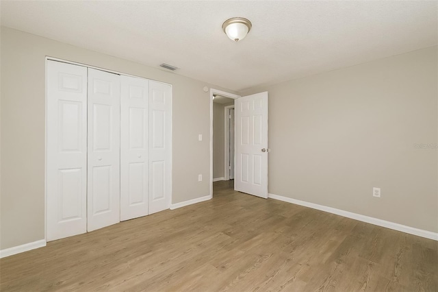 unfurnished bedroom with a closet and light wood-type flooring