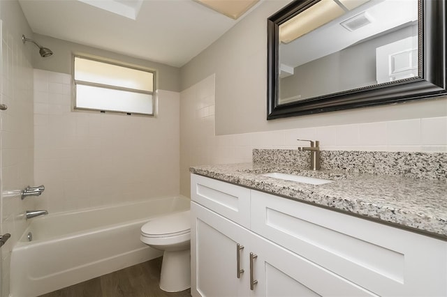 full bathroom featuring vanity, hardwood / wood-style flooring, tiled shower / bath combo, toilet, and backsplash