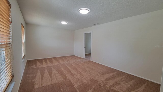 carpeted empty room with a textured ceiling