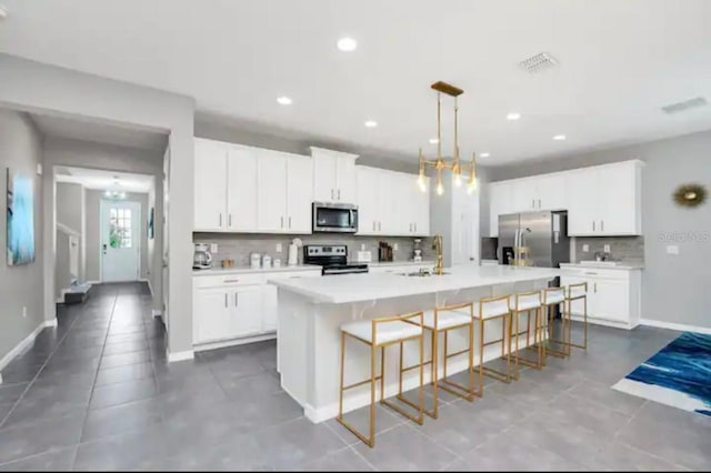 kitchen featuring tile patterned floors, stainless steel appliances, white cabinets, an island with sink, and sink