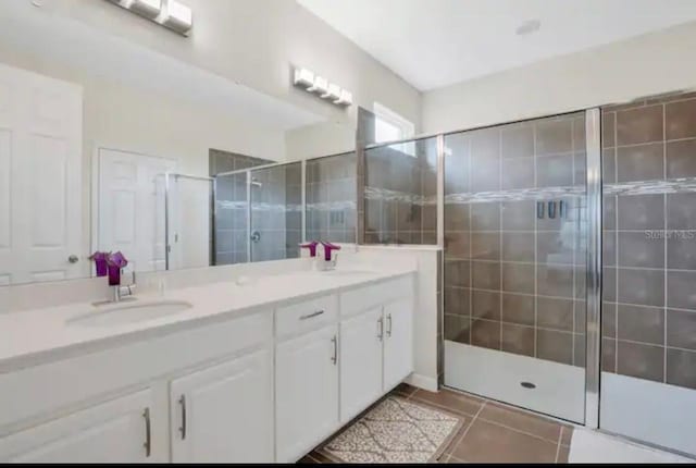 bathroom with dual vanity, an enclosed shower, and tile patterned flooring