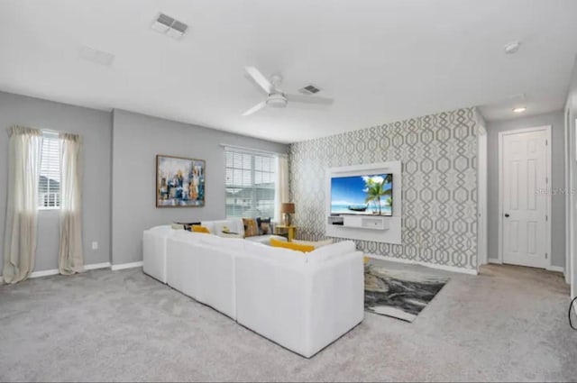 living room with a wealth of natural light, ceiling fan, and carpet flooring