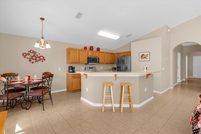 kitchen with appliances with stainless steel finishes, pendant lighting, a chandelier, lofted ceiling, and light tile patterned flooring