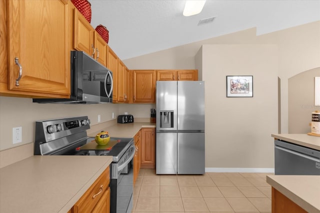 kitchen featuring light tile patterned floors, stainless steel appliances, and lofted ceiling