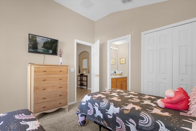 carpeted bedroom featuring vaulted ceiling, ensuite bath, and a closet