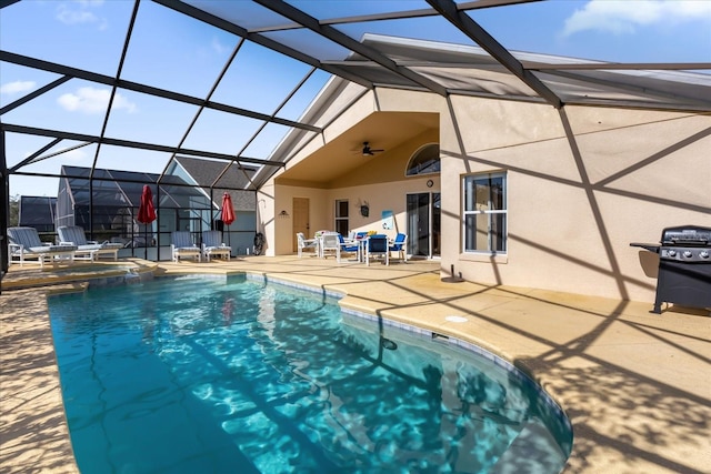 view of swimming pool featuring glass enclosure, ceiling fan, a patio, and an in ground hot tub