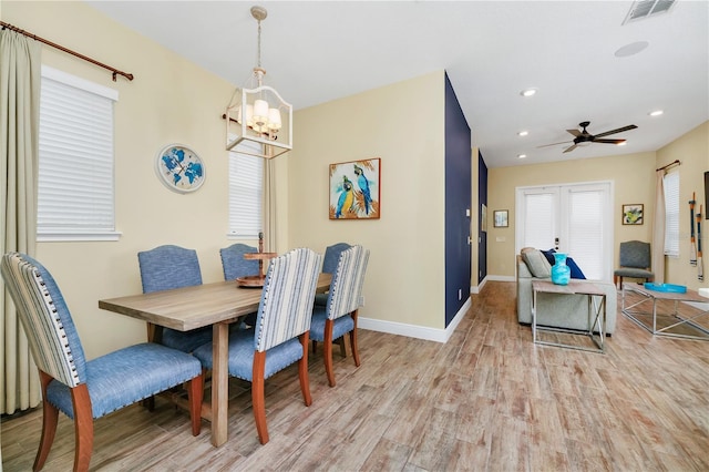 dining area featuring light hardwood / wood-style floors, ceiling fan with notable chandelier, and french doors