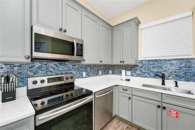 kitchen featuring sink, appliances with stainless steel finishes, gray cabinetry, and tasteful backsplash