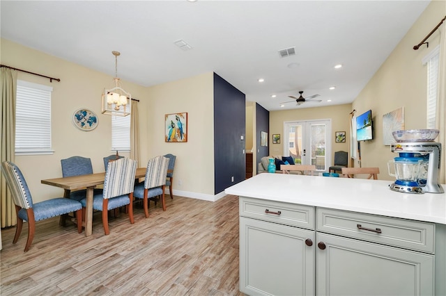 kitchen with ceiling fan with notable chandelier, french doors, light hardwood / wood-style flooring, and pendant lighting